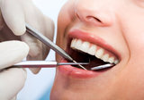 Close-up of patientâ€™s open mouth during oral inspection with mirror and hook Premier Dental Team 3720 NW 43rd Street #102 