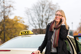 Young woman standing in front of taxi, she gets phone call, Elegant Taxis, Ashford