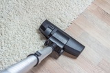 High angle view looking down the handle of a modern vacuum cleaner being used to vacuum a long pile white carpet, Colorado Springs Carpet Cleaning Services, Colorado Springs