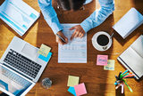 Businesswoman working on a report or questionnaire writing notes with a pen, overhead view of her desk with a laptop, paperwork and coffee Mitch Gibson - Business Coach 53 Cook Parade 
