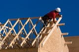 Carpenter with red shirt and white hardhat building a roof of a house at a construction site., Columbia Roofers, Columbia