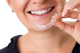 Woman with perfect teeth holding invisible braces, correction teeth braces for night, Coastline Orthodontics, Jacksonville