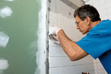 Man applying ceramic tile to a bathtub enclosure wall. , All Seasons Cleaning Ltd., Kingston upon Thames