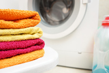 washed towels stacked with washing machine in background, Grande Coin Laundry, San Pedro