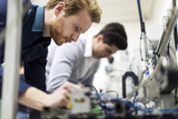 Two young handsome engineers working on electronics components and fixing broken chips, GH Structures, Mineola