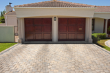 Wooden brown double garage doors of a big house with the drive way in the foreground, Reliable Garage Door Repair North York, North York