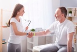 Be in good health. Cheerful and happy female physiotherapist shaking hands with a patient sitting in the medical office, Restore Movement Physiotherapy, Melbourne