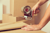 Close up of a guy's hands holding packing machine and sealing cardboard boxes with duct tape, Winslow's Moving Services in Lindale, Lindale